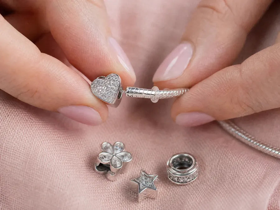 Threading a sterling silver charm onto a bracelet next to a silicone stopper