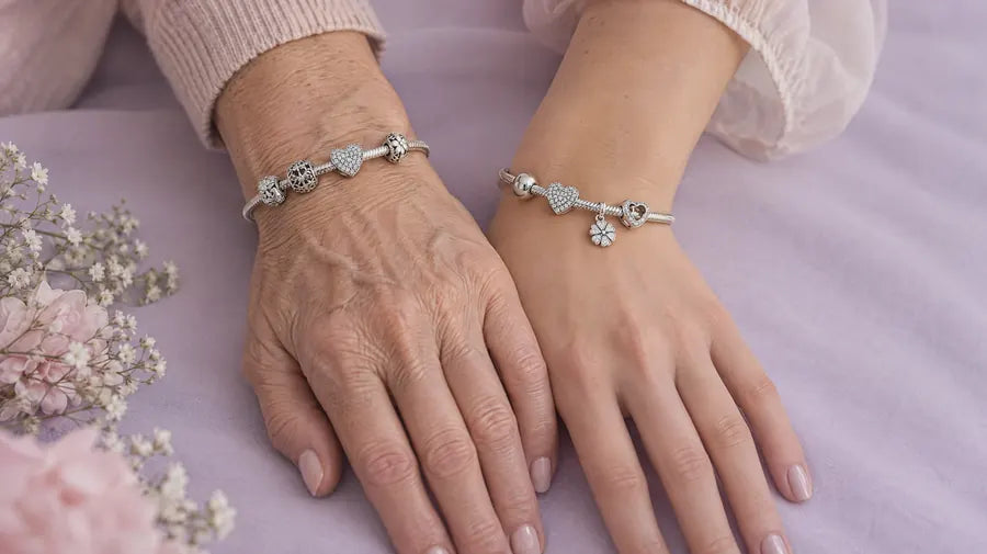 Two wrists side by side, each wearing a sterling silver charm bracelet